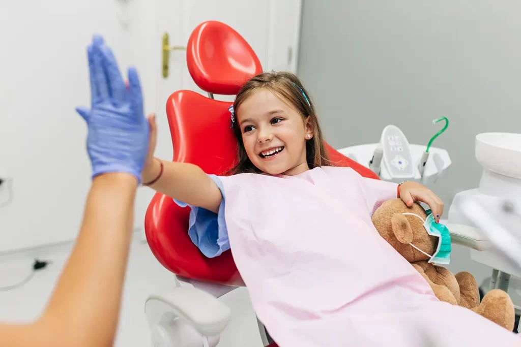 Child giving dentist a high five at the dentist.
