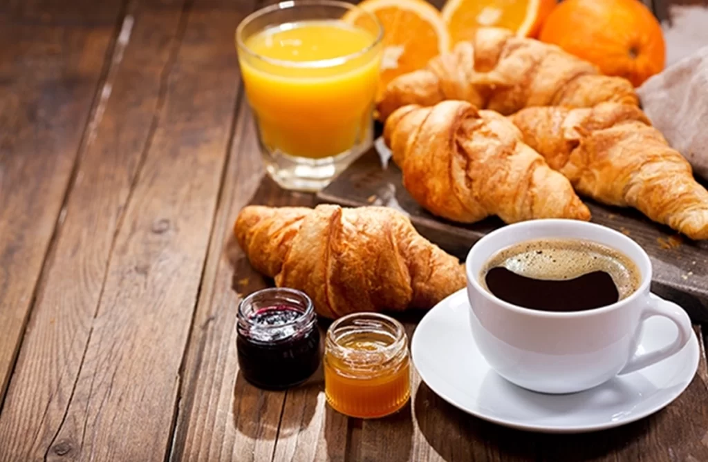 Cup of coffee, croissants, jam, and orange juice.