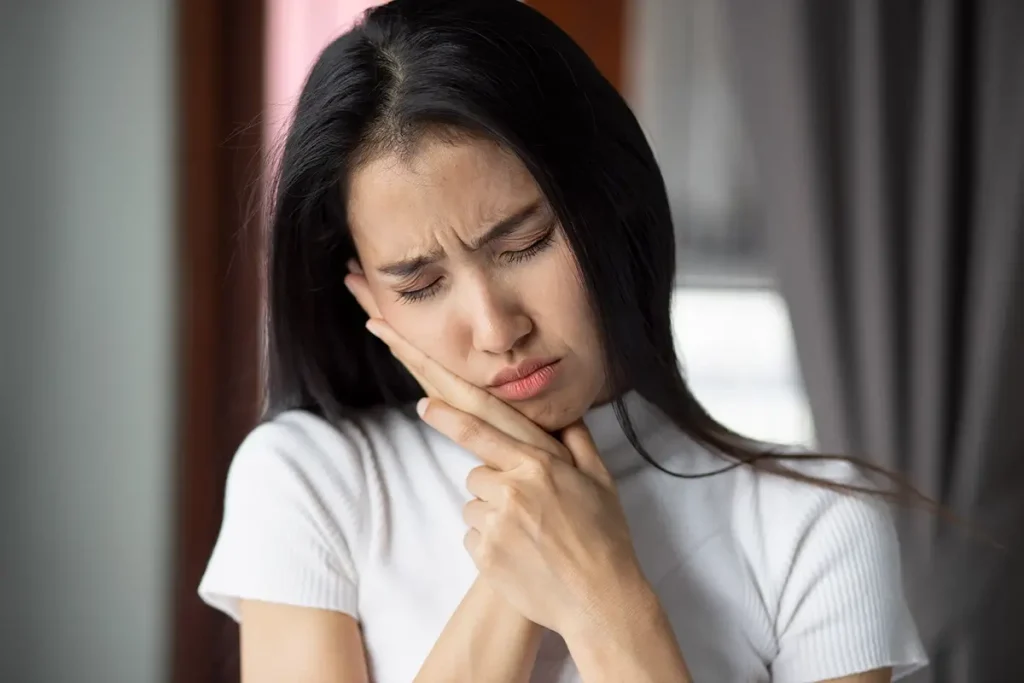 Woman holding mouth due to pain from wisdom teeth